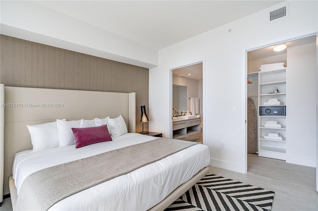 bedroom featuring a walk in closet and light hardwood / wood-style flooring