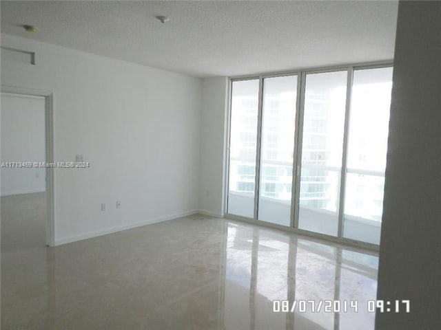 empty room with floor to ceiling windows and a textured ceiling