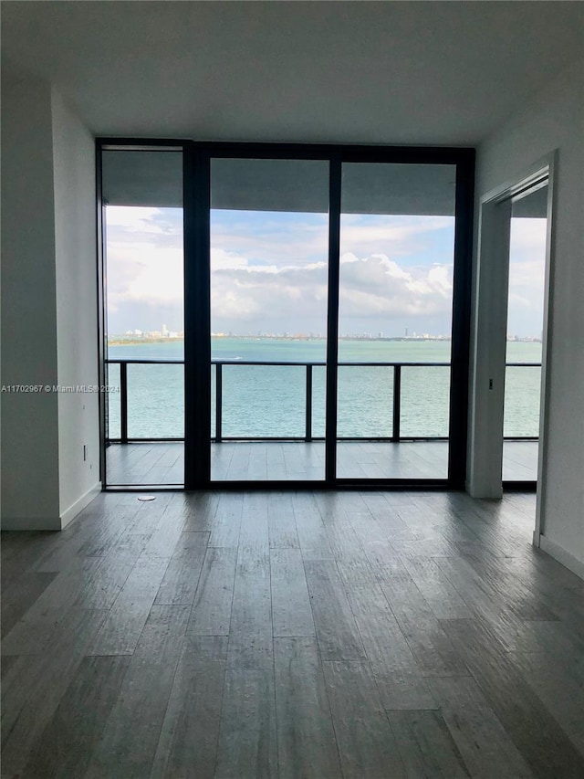 empty room with hardwood / wood-style floors, a water view, and a healthy amount of sunlight