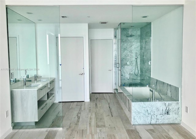 bathroom with hardwood / wood-style floors, vanity, and shower with separate bathtub