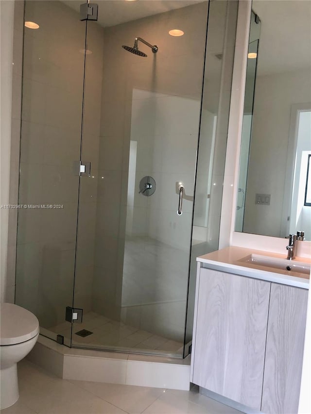 bathroom with tile patterned floors, vanity, toilet, and walk in shower