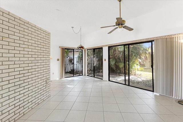 interior space with ceiling fan, light tile patterned floors, and brick wall