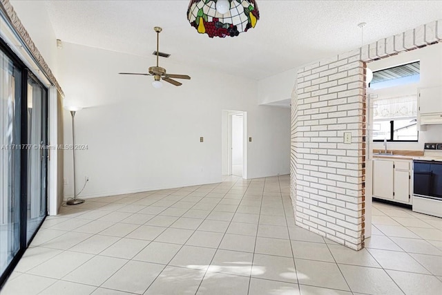 unfurnished living room with ceiling fan, sink, vaulted ceiling, a textured ceiling, and light tile patterned flooring