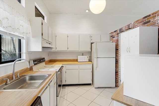 kitchen with sink, brick wall, a textured ceiling, white appliances, and light tile patterned floors