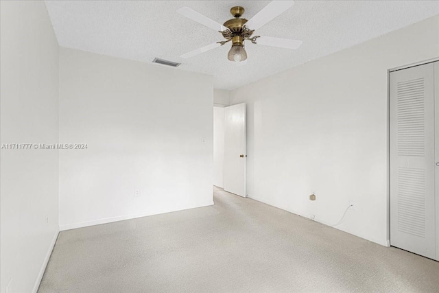 empty room with ceiling fan and a textured ceiling