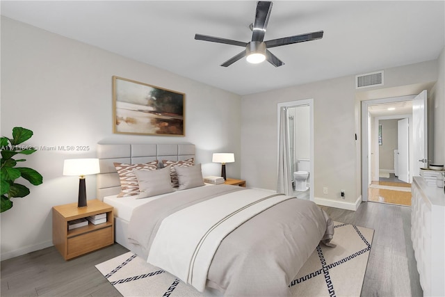 bedroom with visible vents, baseboards, ensuite bathroom, wood finished floors, and a ceiling fan