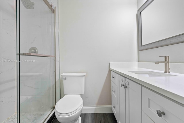 bathroom featuring a shower stall, baseboards, toilet, wood finished floors, and vanity