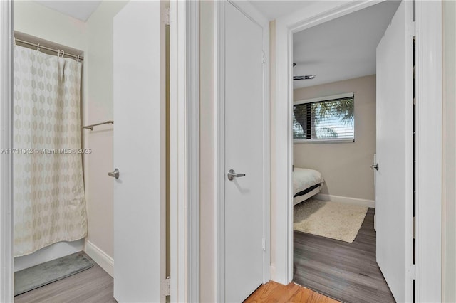 full bath featuring curtained shower, baseboards, and wood finished floors