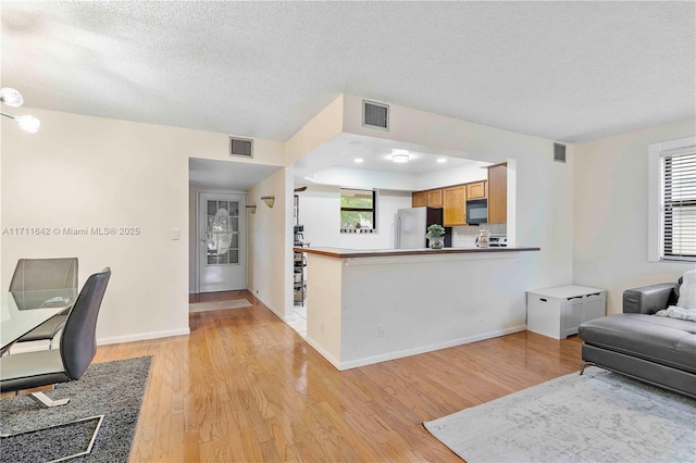 living area with light wood-style floors, visible vents, and baseboards