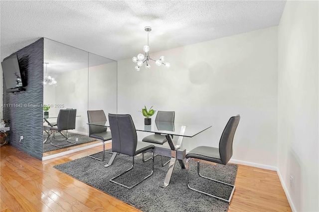 dining room featuring a notable chandelier, baseboards, wood-type flooring, and a textured ceiling