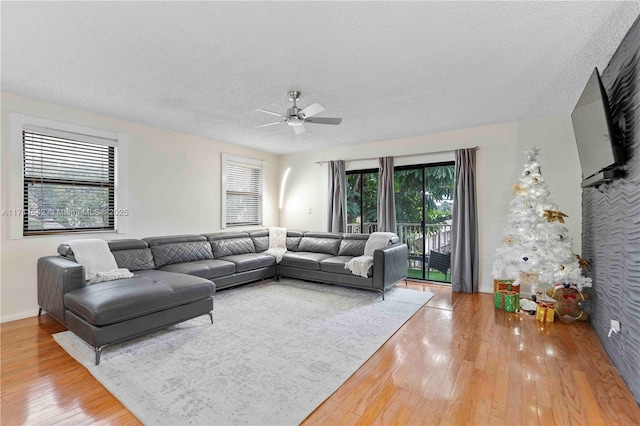 living area with baseboards, a textured ceiling, wood finished floors, and a ceiling fan