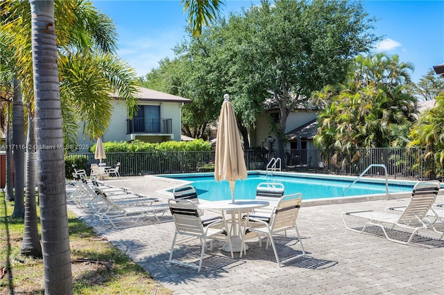 pool with a patio area and fence