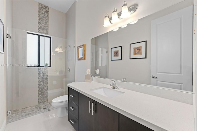 bathroom featuring tile patterned floors, a tile shower, vanity, and toilet