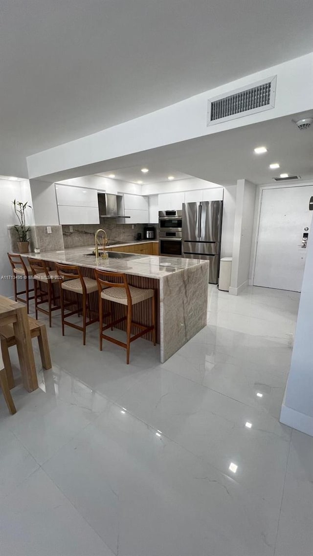 kitchen with a kitchen breakfast bar, white cabinetry, sink, and appliances with stainless steel finishes