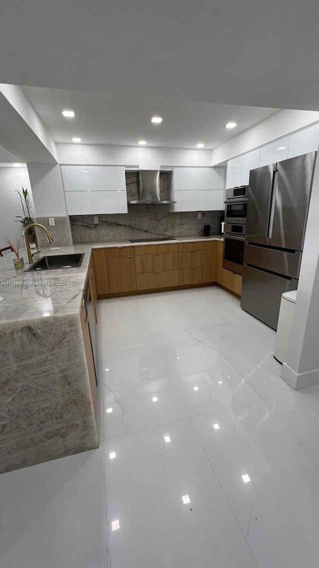 kitchen featuring backsplash, wall chimney exhaust hood, stainless steel appliances, sink, and light tile patterned flooring