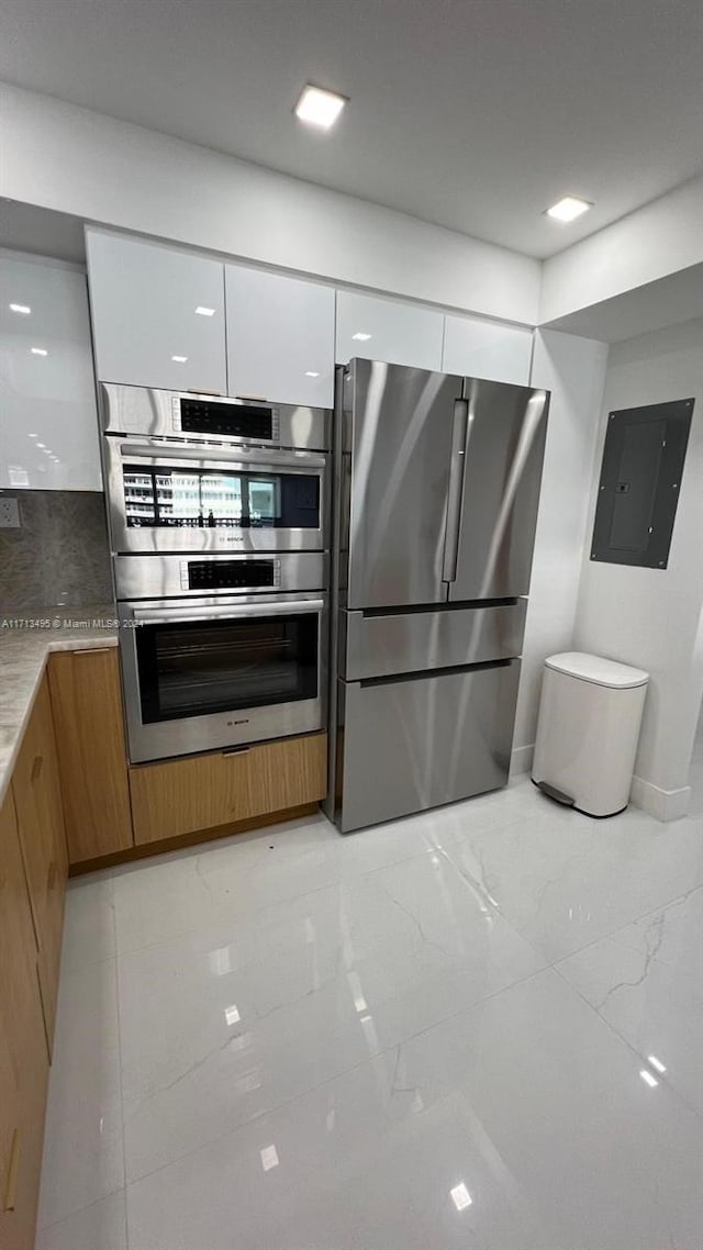 kitchen featuring electric panel, white cabinetry, decorative backsplash, and appliances with stainless steel finishes