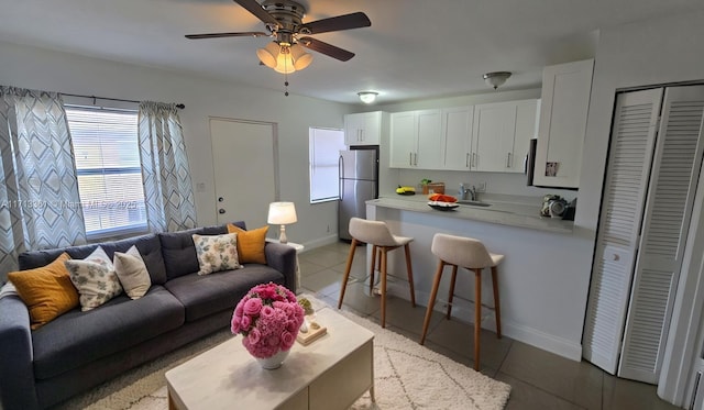 living room with light tile patterned floors, baseboards, and a ceiling fan