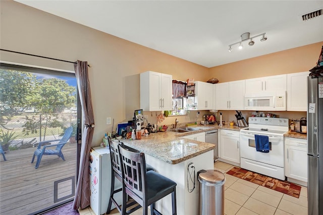 kitchen with stainless steel appliances, visible vents, white cabinets, a peninsula, and a kitchen breakfast bar