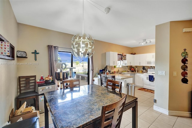 dining area featuring track lighting, a notable chandelier, baseboards, and light tile patterned floors