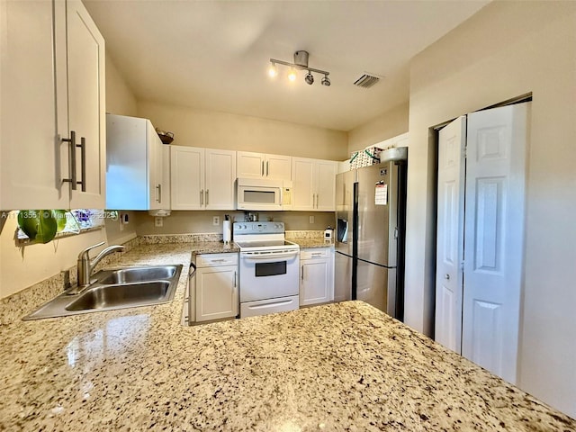 kitchen featuring visible vents, white cabinets, a sink, track lighting, and white appliances