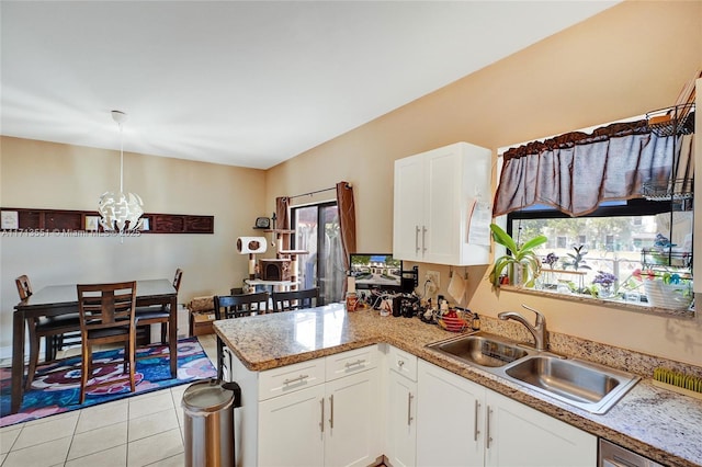 kitchen with decorative light fixtures, light tile patterned floors, white cabinetry, a sink, and a peninsula