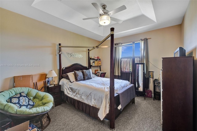 carpeted bedroom with ceiling fan and a raised ceiling