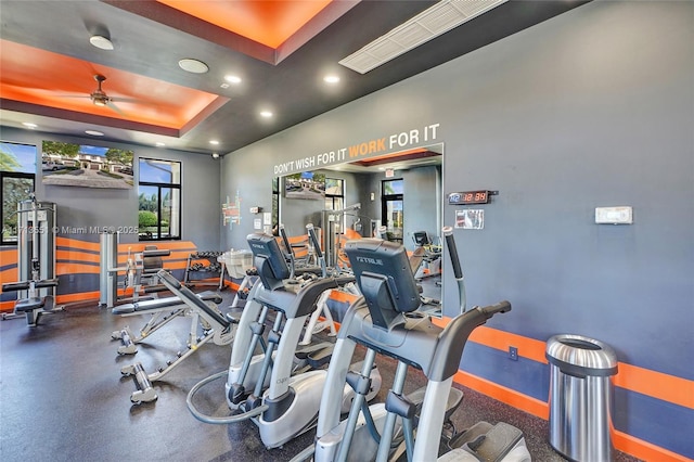 gym with a raised ceiling, a ceiling fan, and recessed lighting