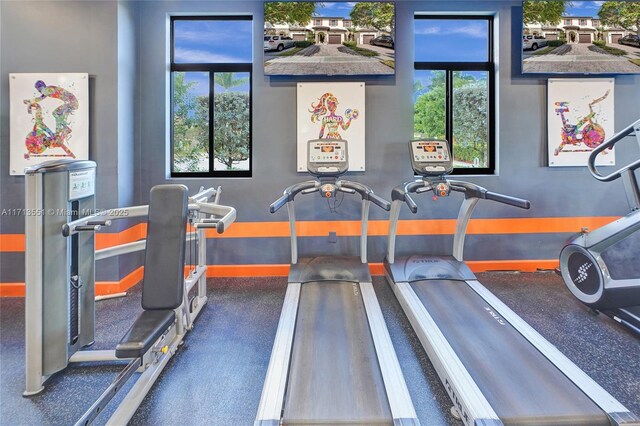 workout area with a raised ceiling and ceiling fan