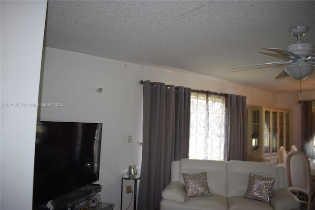 living room with ceiling fan and a textured ceiling