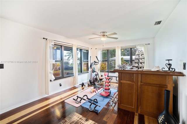 exercise area with ceiling fan and dark wood-type flooring