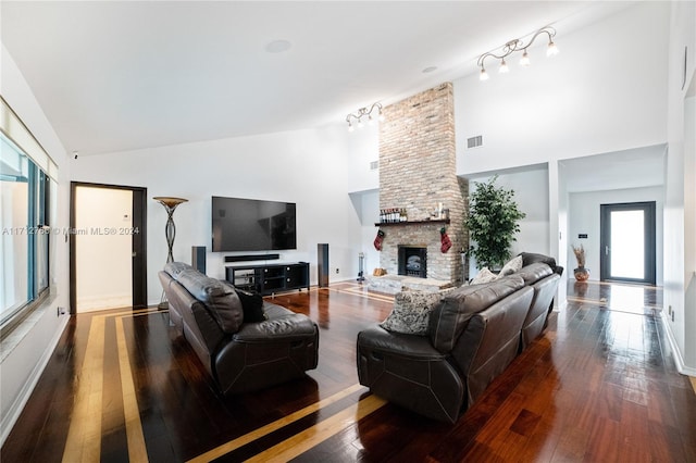 living room with a stone fireplace, dark hardwood / wood-style flooring, and high vaulted ceiling