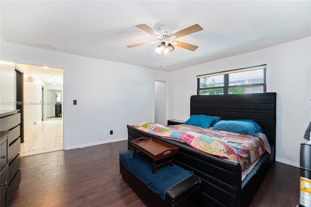 bedroom with a textured ceiling, ceiling fan, and dark hardwood / wood-style floors