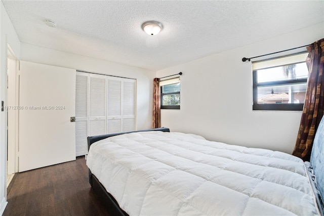 bedroom with dark hardwood / wood-style flooring, a textured ceiling, and a closet