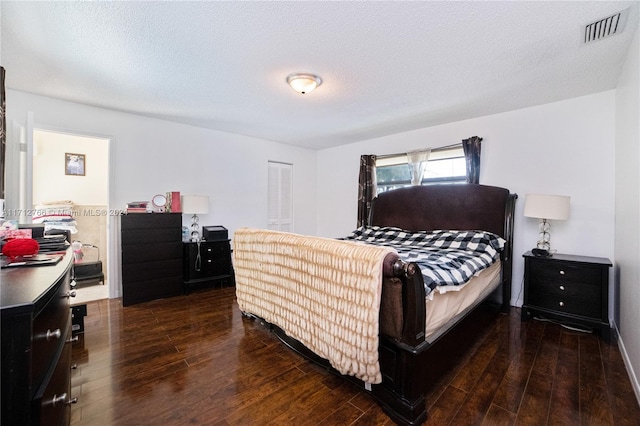 bedroom featuring dark hardwood / wood-style flooring, a textured ceiling, and a closet