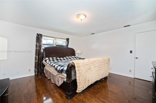 bedroom with a textured ceiling and dark hardwood / wood-style flooring