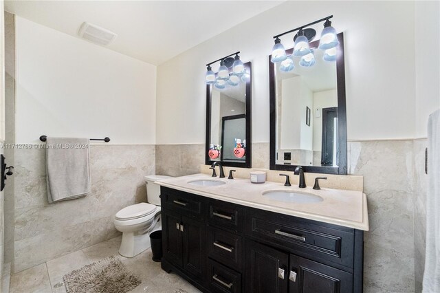 bathroom with tile patterned floors, vanity, toilet, and tile walls