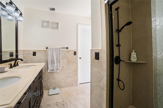 bathroom with a shower, vanity, tile patterned floors, and tile walls