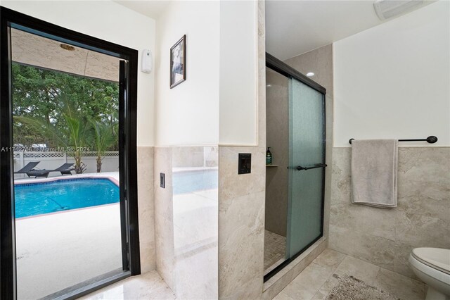 bathroom with toilet, walk in shower, and tile walls