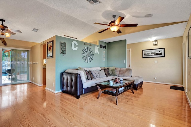 living room with ceiling fan, light hardwood / wood-style floors, and vaulted ceiling