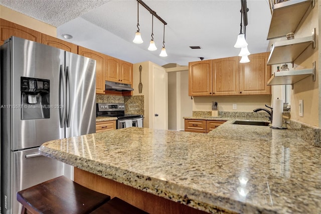 kitchen featuring track lighting, hanging light fixtures, sink, decorative backsplash, and appliances with stainless steel finishes