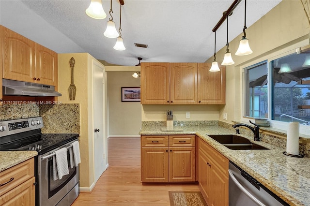 kitchen with pendant lighting, sink, light stone countertops, tasteful backsplash, and stainless steel appliances