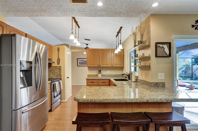 kitchen with kitchen peninsula, appliances with stainless steel finishes, a textured ceiling, sink, and pendant lighting