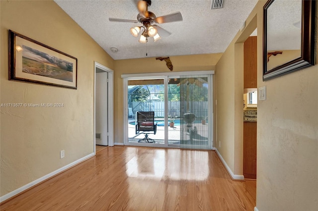 empty room featuring lofted ceiling, ceiling fan, light hardwood / wood-style flooring, and a textured ceiling