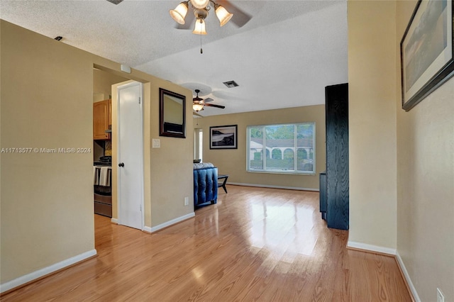 unfurnished living room with ceiling fan, a textured ceiling, and light wood-type flooring