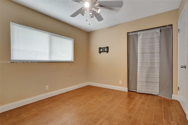 spare room with ceiling fan, a textured ceiling, and light wood-type flooring