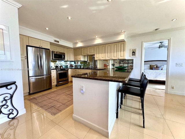 kitchen featuring a breakfast bar, sink, light tile patterned floors, appliances with stainless steel finishes, and kitchen peninsula