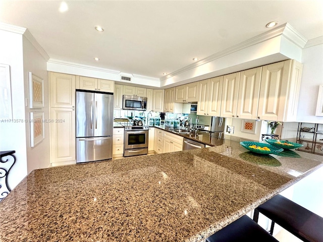 kitchen with kitchen peninsula, appliances with stainless steel finishes, a kitchen bar, and sink