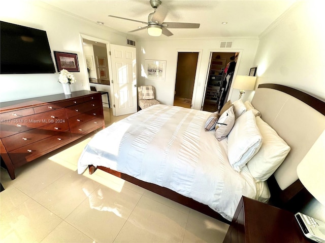 tiled bedroom featuring ceiling fan, a closet, a spacious closet, and ornamental molding