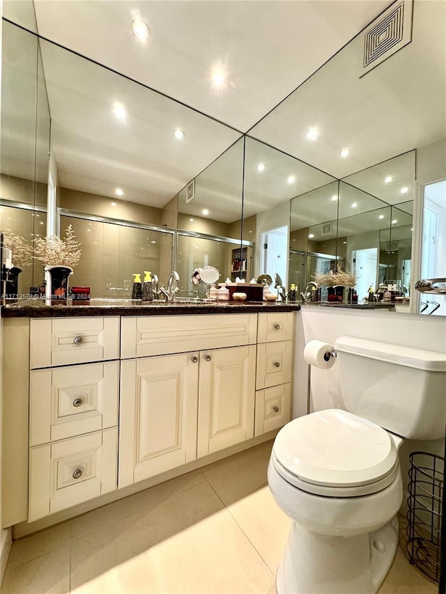 bathroom with toilet, vanity, tile patterned floors, and a shower with door