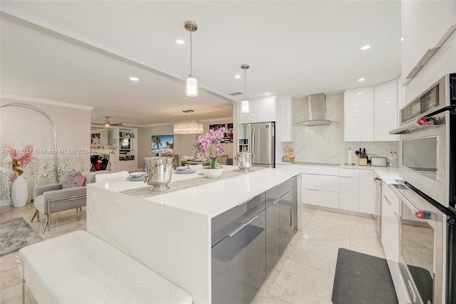 kitchen with white cabinets, a kitchen island, wall chimney range hood, and appliances with stainless steel finishes